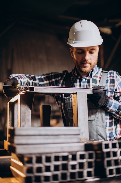 Workman wearing har hat with measuring ruler at factory