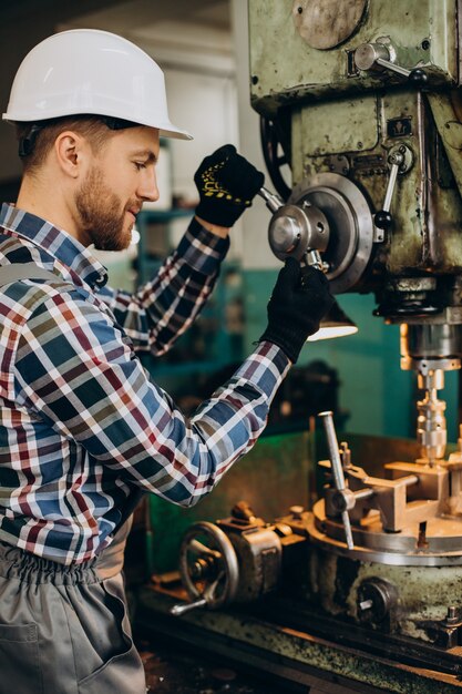 Workman wearing hard hat working with metal constructions at factory