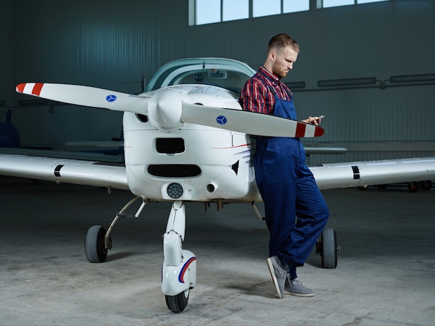 Workman with smartphone and a plane