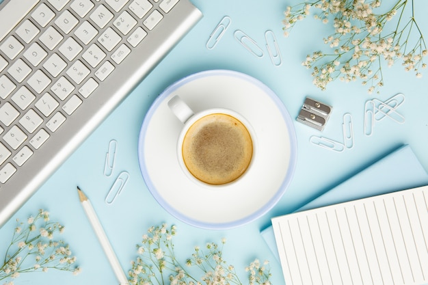 Free photo workplace arrangement on blue background with cup of coffee