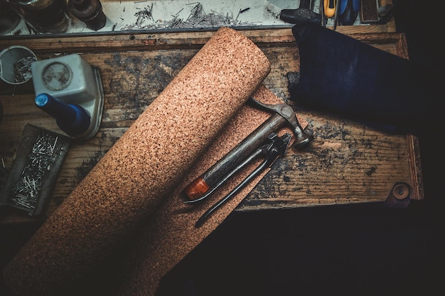 Workplace bench of cobbler with different tools on it and peace of textured fabric.