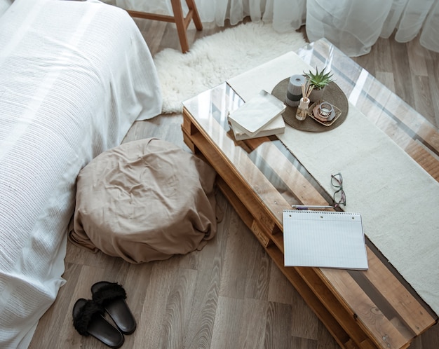 Posto di lavoro a casa con un tavolo con libri e un quaderno e un comodo pouf accanto.