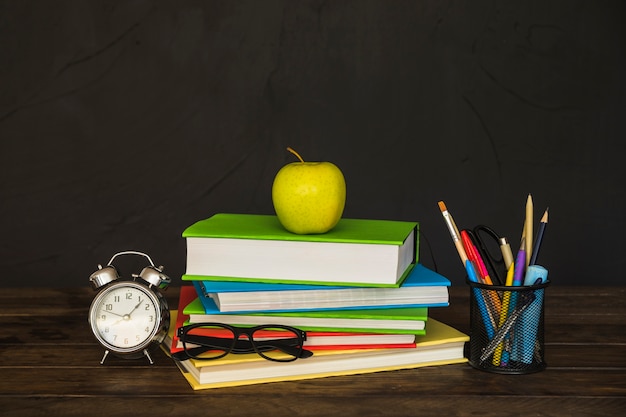 Workplace with books glasses alarm clock and stationery