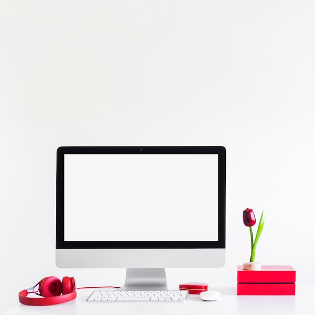 Workplace with keyboard near monitor, computer mouse and headphones