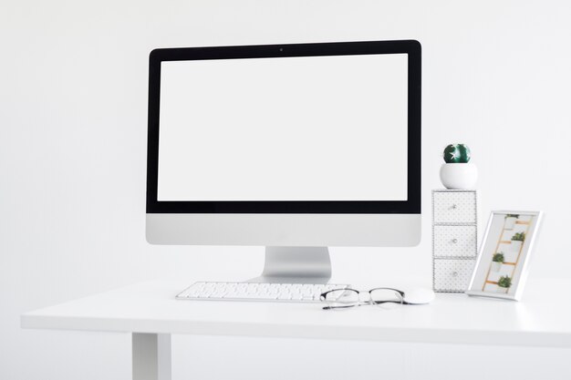 Workplace with keyboard near monitor and eyeglasses