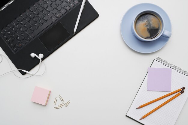 Workplace with laptop, coffee and notepad, top view, copyspace