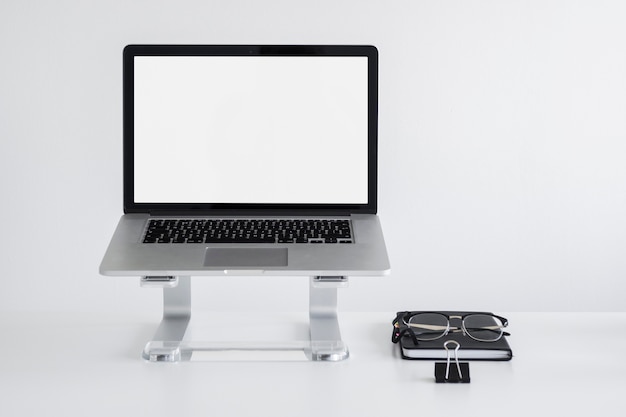 Workplace with laptop on stand near eyeglasses