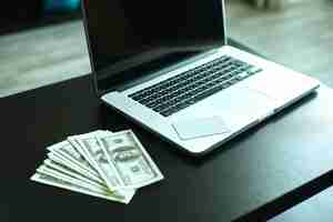 Free photo workplace with money and notebookus dollar banknotes near laptop