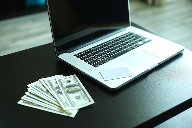 Workplace with money and notebookUS dollar banknotes near laptop