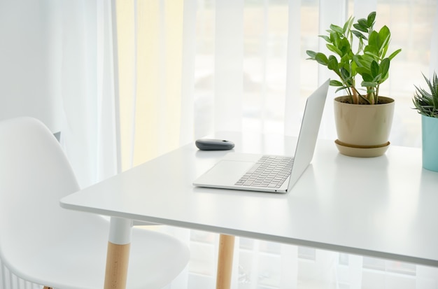 노트북 노트북이 있는 직장 사무실 창문과 도시 전망의 편안한 작업 테이블.