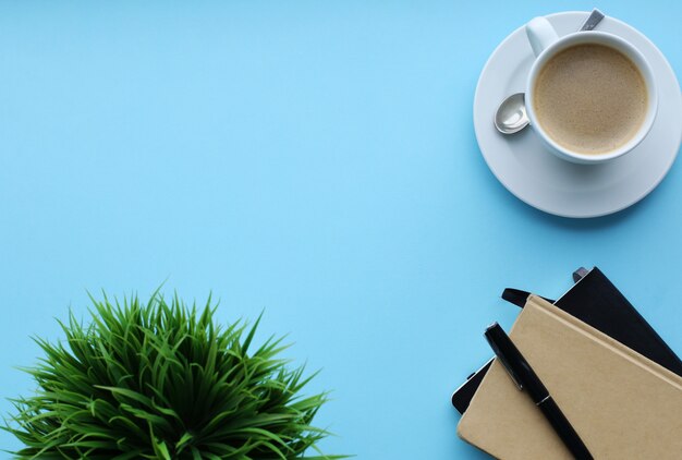 Free photo workplace with plant, notebooks and coffee cup