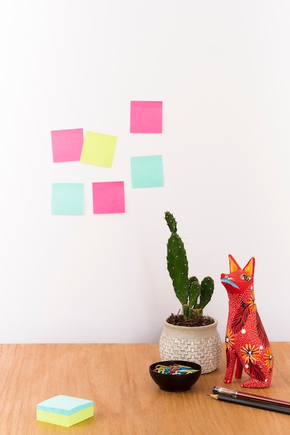 Foto gratuita area di lavoro con cactus in vaso e figurina sulla scrivania