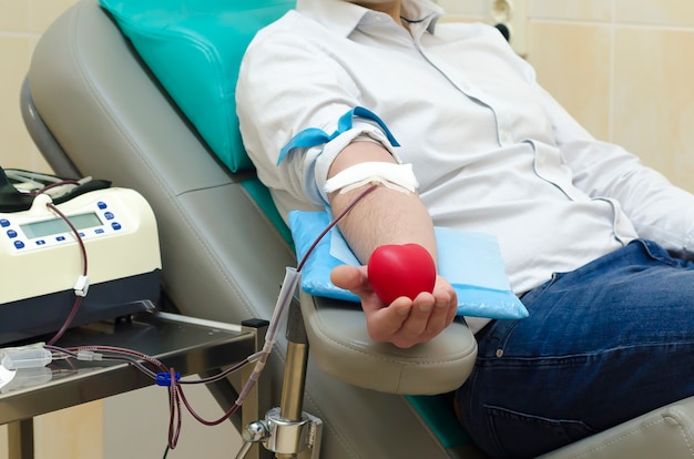 世界​献血者​デー​6​月​14​日​。​静脈​から​血液​検査​を​行う​手​。​寄付​。​病院​の​輸血​部門​。​男​は​手​に​ハート​の​形​で​弾む​ボール​を​保持しています​。