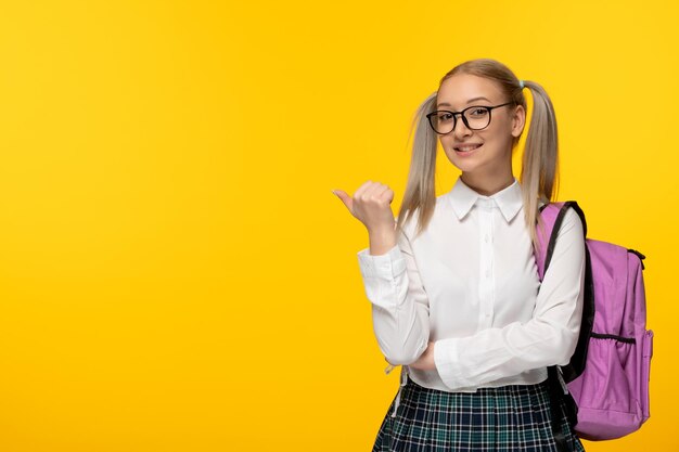 World book day girl with pony tails and pink backpack on yellow wallpaper