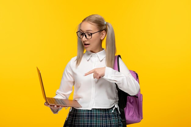 ノートパソコンを見てかわいい制服を着た世界の本の日のスマート女子高生