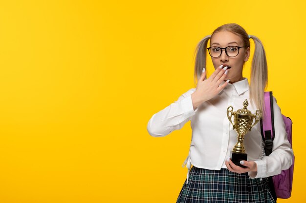 World book day surprised schoolgirl with pony tails holding a golden trophy