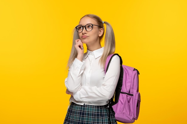 World book day thinking blonde schoolgirl in glasses and pink backpack