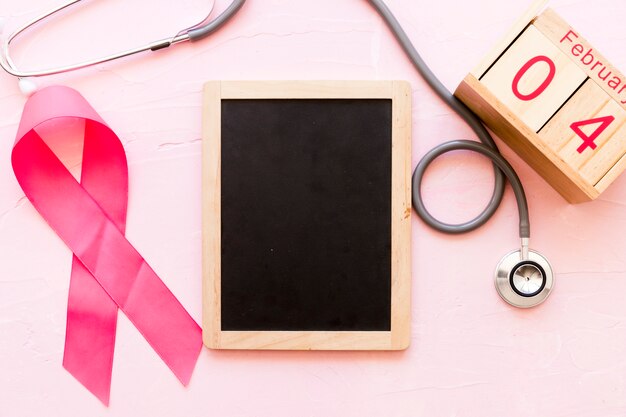 World cancer day awareness ribbon with stethoscope, wooden slate and 4th February wooden box