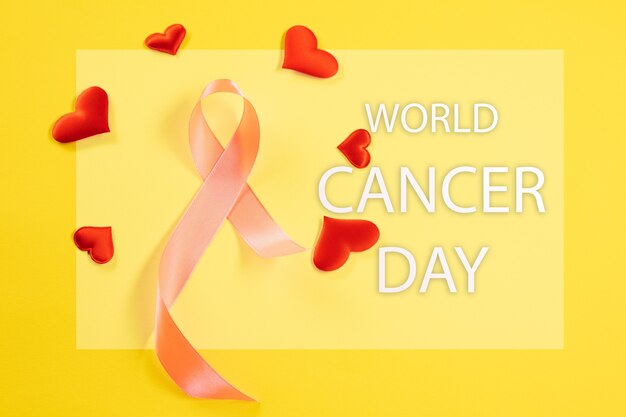 World cancer day card with pink ribbon and red hearts