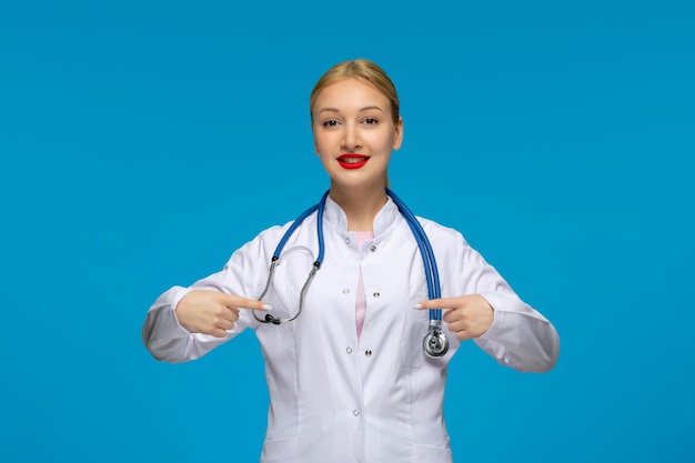 World doctors day smiling doctor pointing at herself with the stethoscope in the medical coat