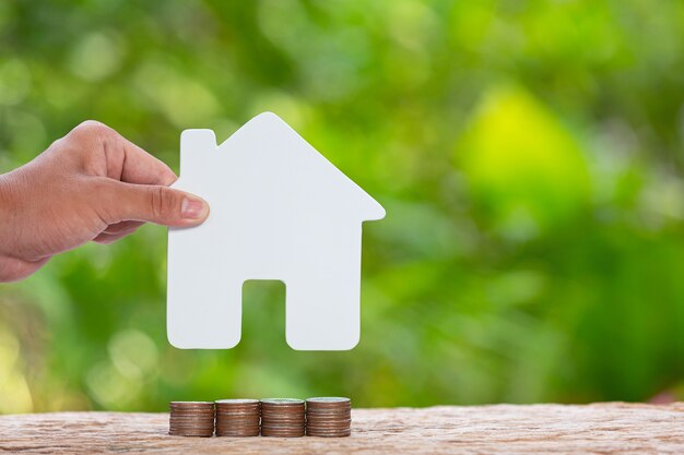 world habitat day,close up picture of a pile of coins andhand holding  a model house