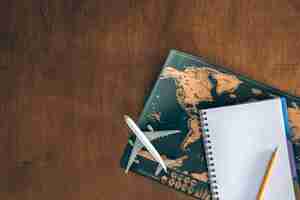 Free photo world map airplane miniature and notepad on a wooden table top view