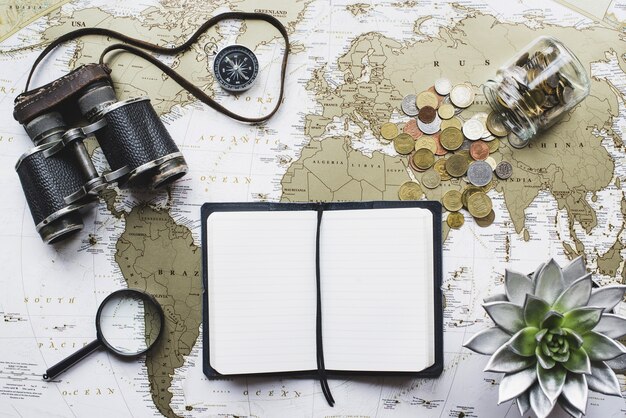 World map background with blank notebook and binoculars