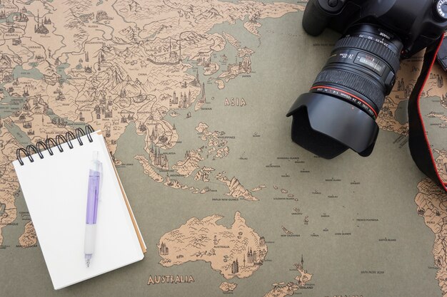 World map background with decorative camera and notebook