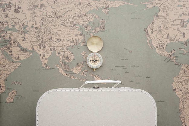 World map background with suitcase and compass