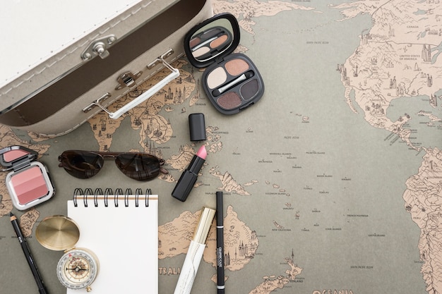 World map background with suitcase and make-up