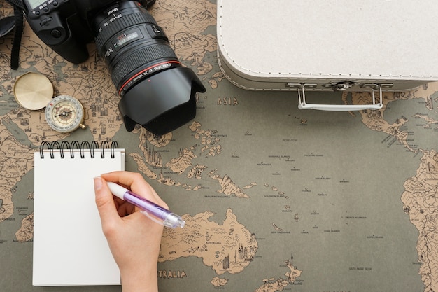World map background with travel items and hand writing