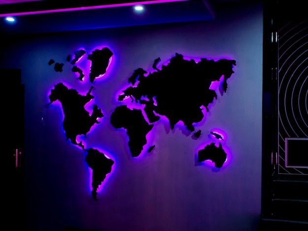 World map installed on the wall with purple neon lights in the dark room
