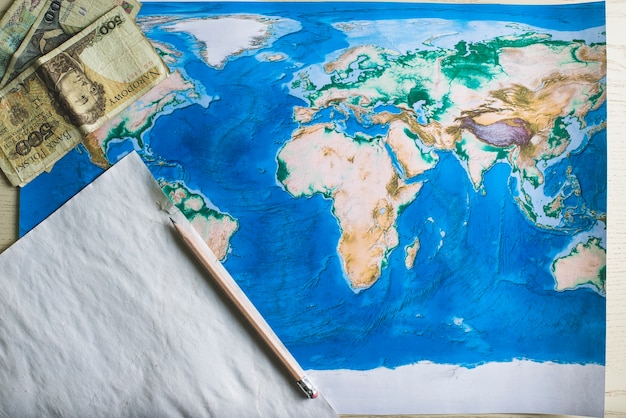 World map with piece of paper and banknotes