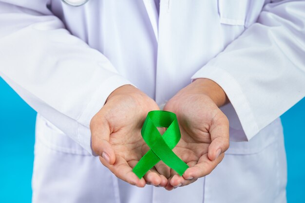 세계 정신 건강의 날. 의사의 손을 잡고 녹색 리본