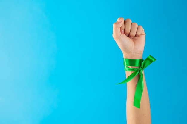 Всемирный день психического здоровья. зеленые ленты, завязанные на запястье на синем фоне