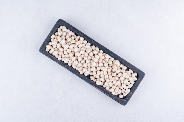 Free photo worn-out tray filled with a portion of raw chickpeas on marble surface