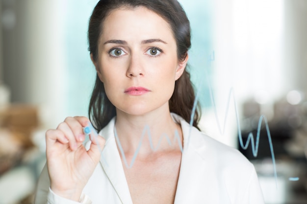 Worried Adult Businesswoman Drawing Graph on Glass