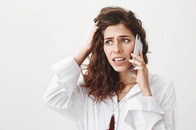 Worried and alarmed woman talking on phone, got in trouble