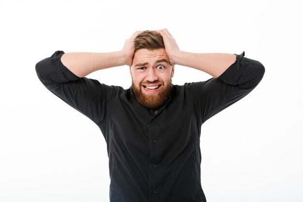 Worried bearded man in shirt holding his head