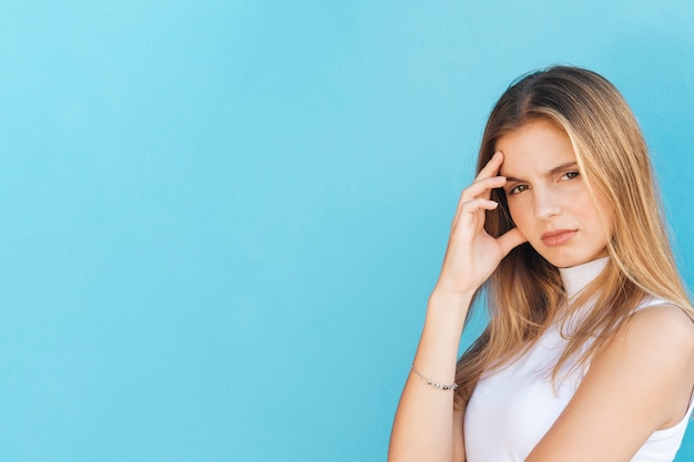 Foto gratuita giovane donna bionda preoccupata contro il contesto blu