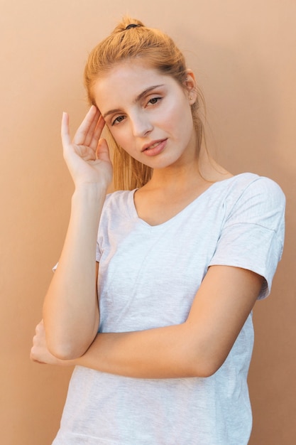 Free photo worried blonde young woman having headache against beige background