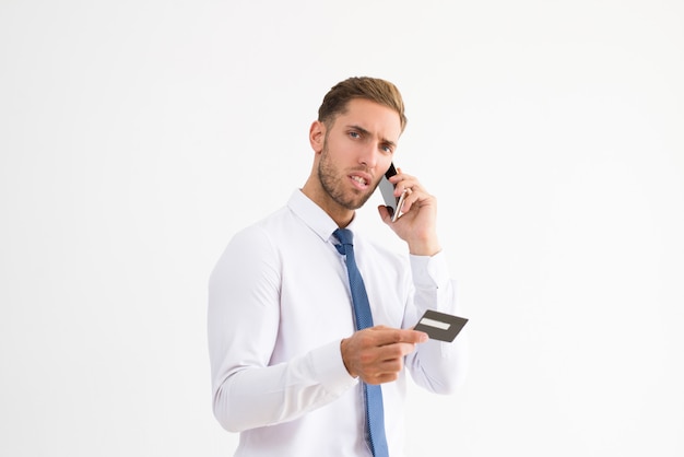 Worried business man holding credit card and talking