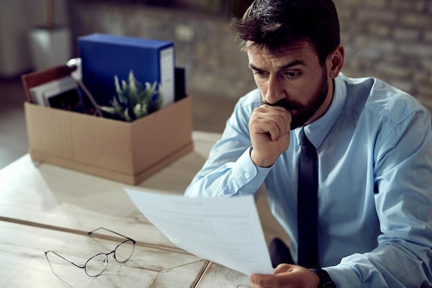 Worried businessman going through paperwork after losing his job in the office