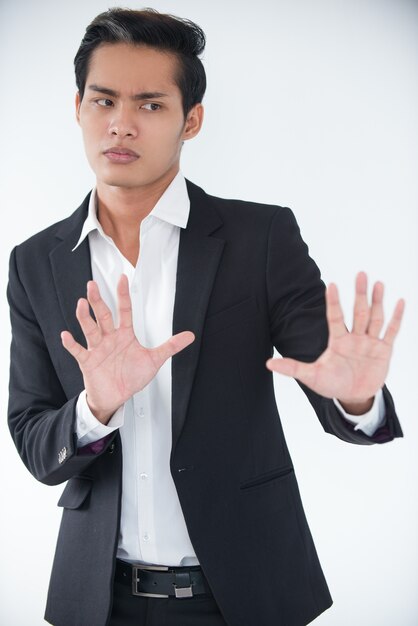 Worried businessman protecting himself with hands