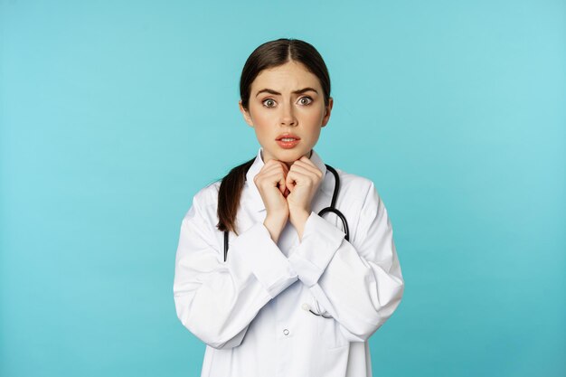 Worried and concerned physician hospital worker in white lab coat looking scared and nervous at came...