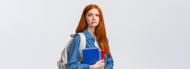 Free photo worried cute and nervous redhead teenage girl scared parents scold her for skipping class biting lip