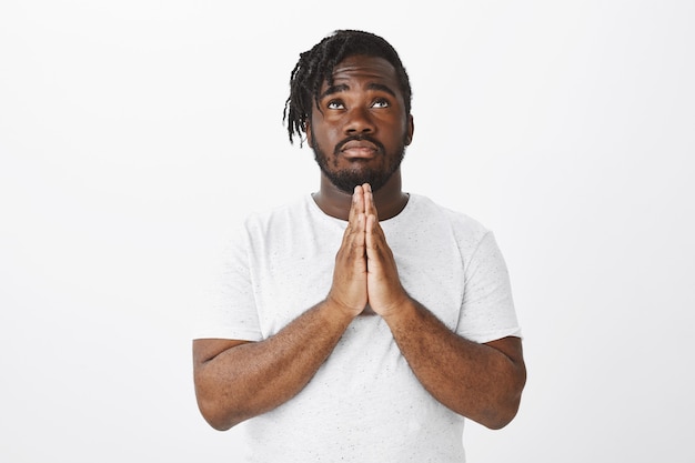 Worried guy with braids posing against the white wall