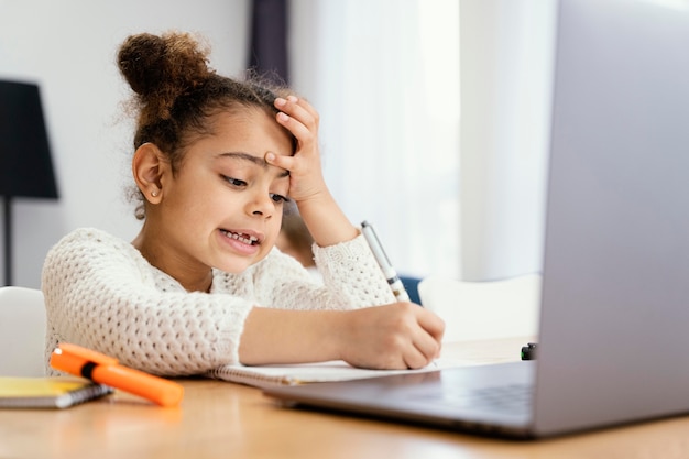 Free photo worried little girl at home during online school with laptop