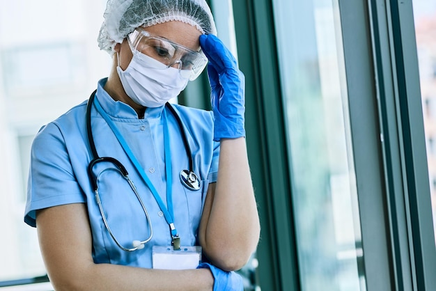 코로나 바이러스 전염병 동안 병원에서 일하는 동안 두통을 앓고 있는 걱정스러운 간호사