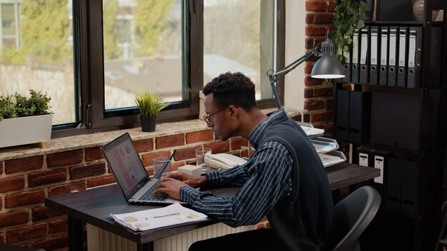 Worried person doing financial paperwork under pressure, feeling stressed and desperate. African american man failing to work on business plan before deadline, feeling depressed about failure